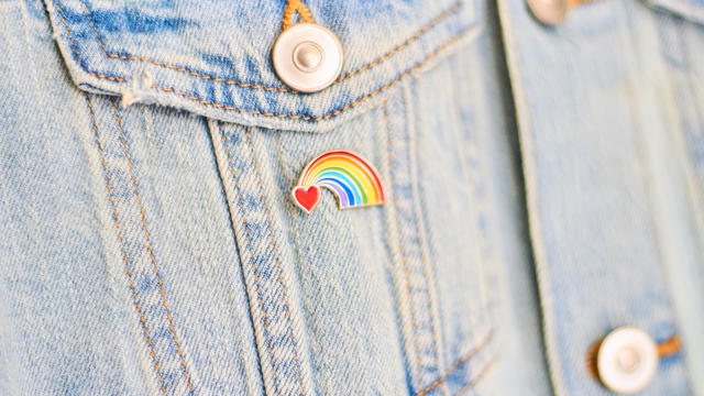 Close-up of a heart rainbow badge on denim jacket pocket 