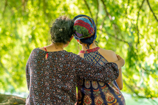 A woman sitting next to her sister who has cancer. She is wearing a headscarf. 