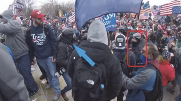 A screenshot of a video allegedly showing Peter Moloney, highlighted in red, advancing toward an Associated Press photographer, indicated by the blue arrow, on Jan. 6, 2021. 