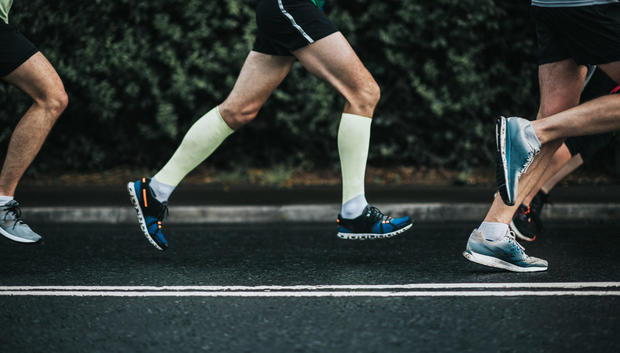 Joggers, pictured from the waist down, running from left to right on tarmac 