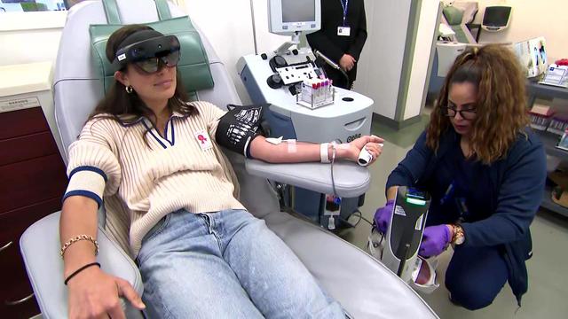 A woman wears mixed-reality glasses while donating blood. 
