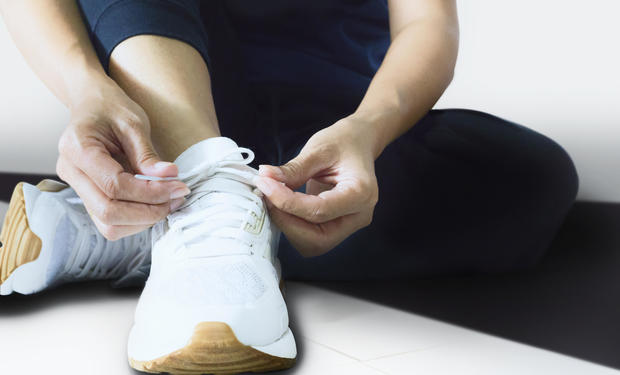 Close up of woman tying shoelaces on white running shoe 