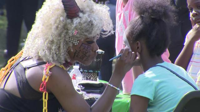 A woman paints a child's face at a Juneteenth festival. 