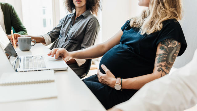Pregnant Woman Working With Colleagues At Office 