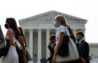 A group of people wear face masks to protect against air pollution as they walk past the Supreme Court Building on June 29, 2023, in Washington, D.C. 