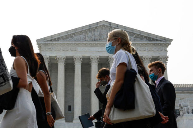 A group of people wear face masks to protect against air pollution as they walk past the Supreme Court Building on June 29, 2023, in Washington, D.C. 