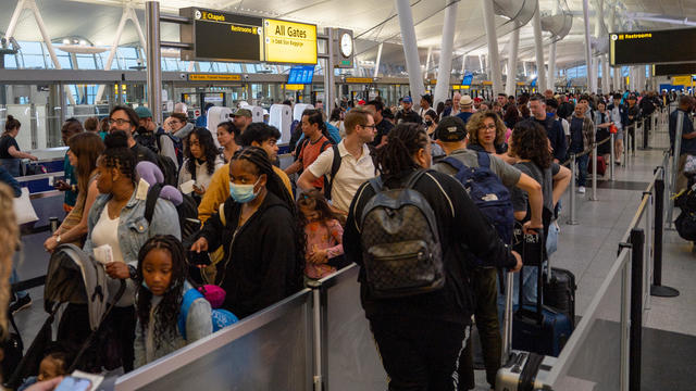 People wait in line at the security check-in of JFK International airport on June 30, 2023 in New York City. 