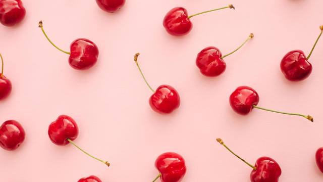 Red cherry summer fruits over pink background 