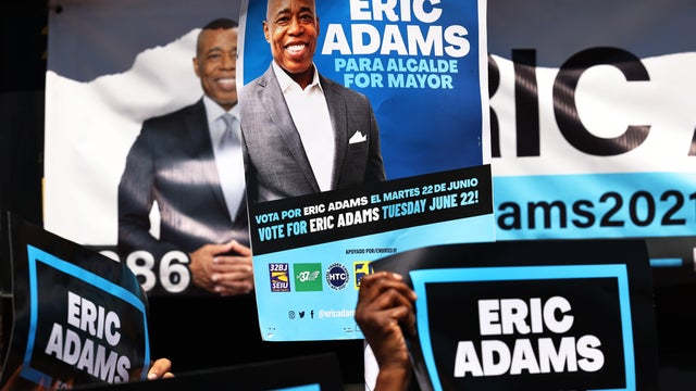 People hold up campaign signs as New York City mayoral candidate Eric Adams speaks during a press conference outside his campaign office on June 17, 2021 in the Harlem neighborhood of Manhattan in New York City. 