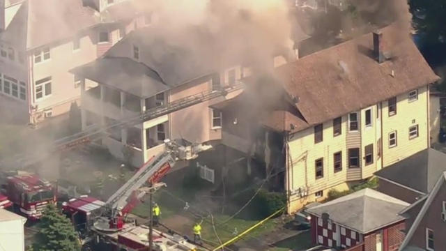 An aerial view of firefighters battling a fire at a two-story multi-family home. 