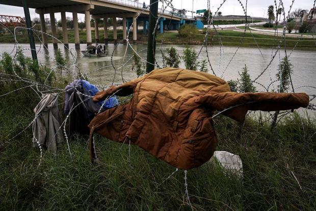 Discarded clothes are over a barb wire fence in front of the Rio Grande in an area where migrants cross in Eagle Pass, Texas on Dec. 19, 2022. 