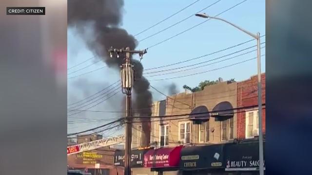 Black smoke pours from the window of a building in Queens. 