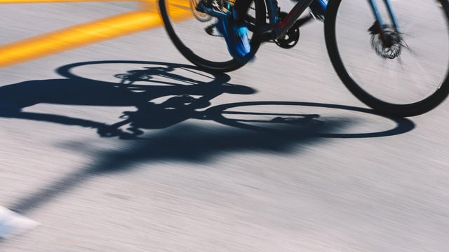 Abstract Sports Background. Light And Shadows Cyclist Silhouette At The Asphalt Road Background 