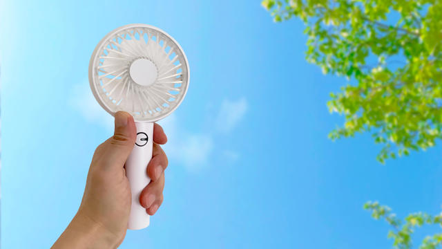 Portable electric fan held in the left hand 
