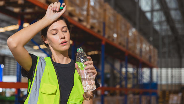 Tired stress woman staff worker sweat from hot weather in summer working in warehouse goods cargo shipping logistics industry. 