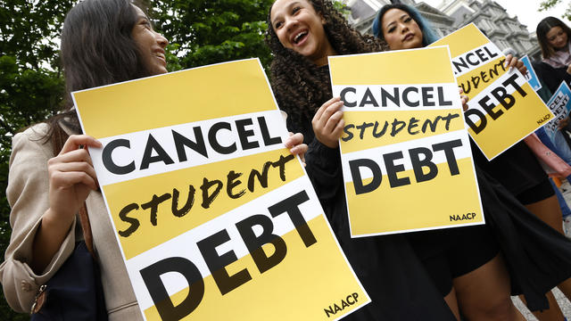 Protesters hold signs reading "Cancel student debt" 