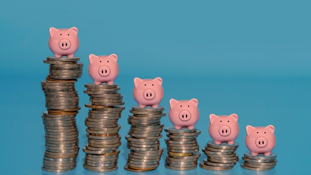 Piggy banks standing on top of stacks coins. 