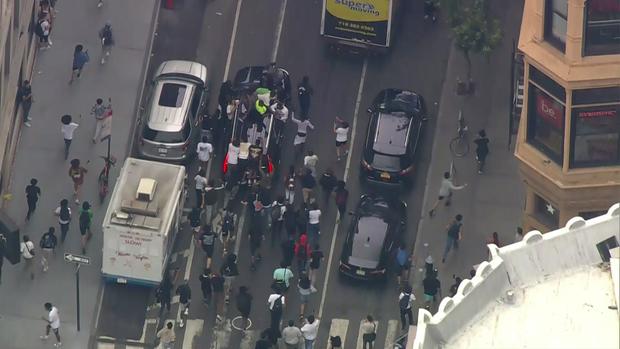 An aerial view of dozens of people chasing an SUV as it leaves the Union Square area. 