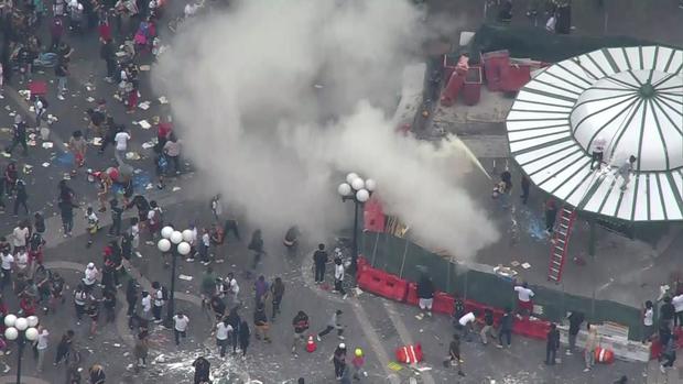 An aerial view of people crowded into Union Square. One person sets off a fire extinguisher. 
