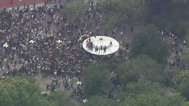 An aerial view of thousands of people crowded into Union Square. Several people stand on the roof of a structure. 