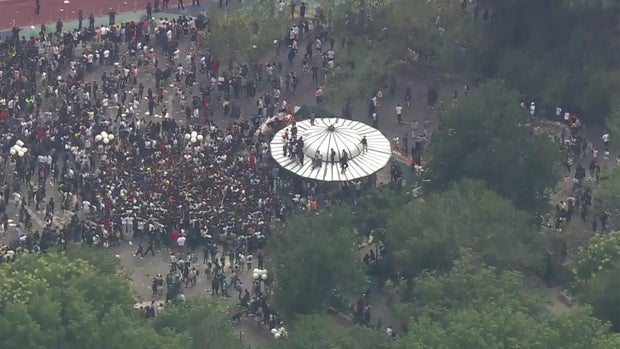 An aerial view of thousands of people crowded into Union Square. Several people stand on the roof of a structure.