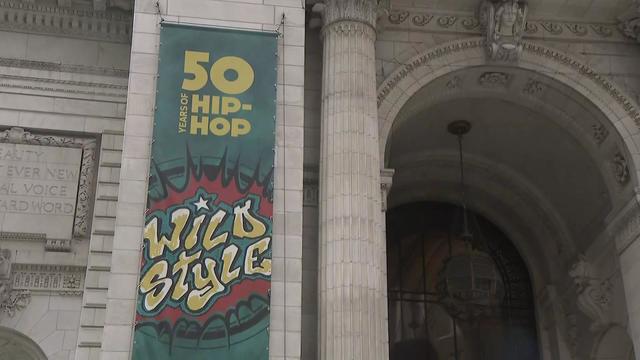 The exterior of the New York Public Library with a banner that says "50 years of hip-hop wild style." 