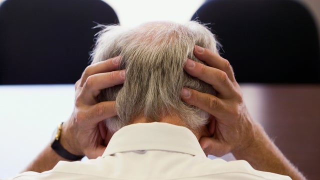 Senior Man Holding Head in Hands 