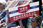 An attendee uses a sign to shield the sun during a rally on Sunday, Aug. 6, 2023, in Norwood, Ohio. 