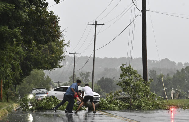 Motorists stop to remove a fallen tree from the roadway following a storm in Maryland. 