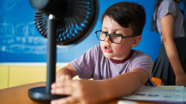 School boy interacting with electric fan at classroom 