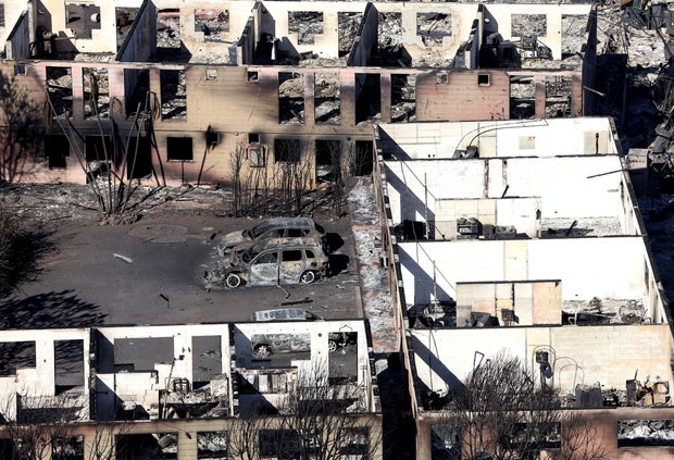 Burned cars sit in front of an apartment building that was destroyed by a wildfire in Maui