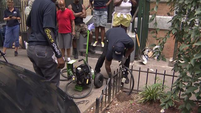 City workers put rat mitigation efforts into effect in Harlem as residents watch. 