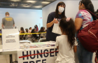 migrants talk to an advocate at a table marked Hunger Free NYC 