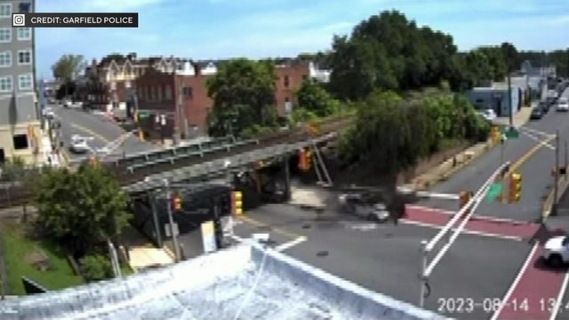 Surveillance video shows a white sedan slamming into and knocking down a light post. 