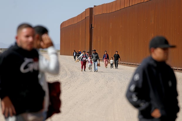 Immigrants walk along the border wall to turn themselves over to Border Patrol agents along the U.S.-Mexico border on Thursday, May 11, 2023 in San Luis Río Colorado in Mexico.