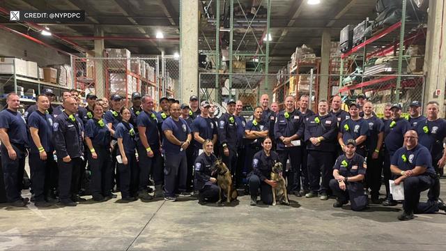 Members of New York Task Force One pose for a photo inside a warehouse. 