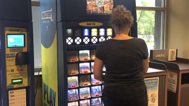 Woman purchasing scratch off Lottery Tickets at Quic Pic machine in Whole Foods, Boston, Massachusetts 