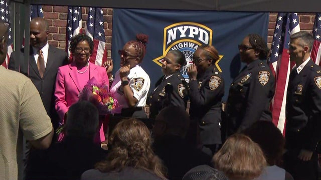NYPD Transportation Chief Kim Royster holds a bouquet of flowers as she stands with other NYPD members at a ceremony. 