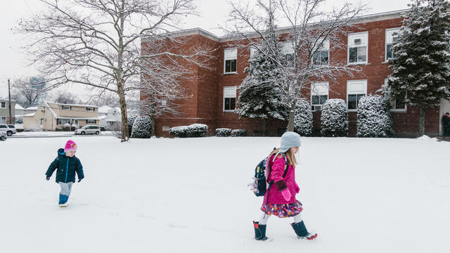 Two children walk to school in the snow. 