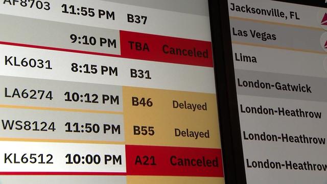 Flights displayed as canceled and delayed on a flight status board at JFK Airport. 