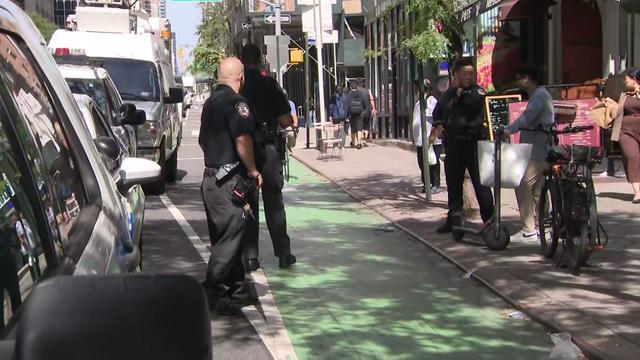 NYPD officers monitor a bike lane and speak to a scooter rider. 