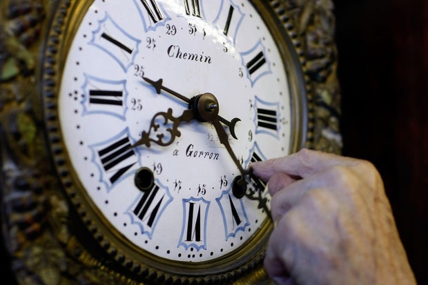 Howie Brown adjusts the time on a clock back one hour for the end of daylight saving time at Brown's Old Time Clock Shop, Nov. 2, 2007, in Plantation, Florida.