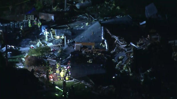 Firefighters search through the collapsed rubble of a home in West Milford.