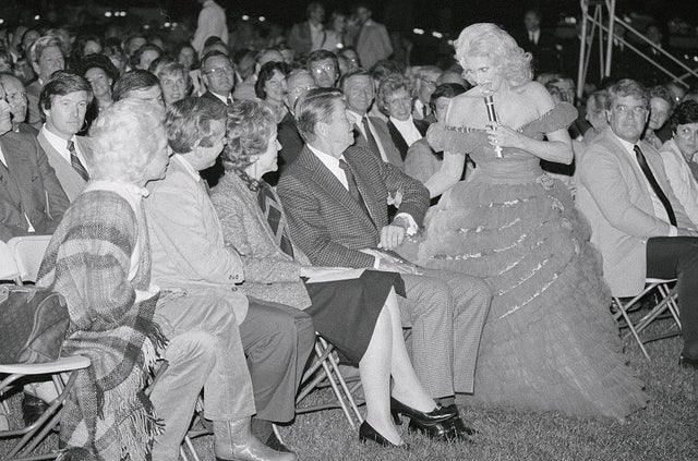 Singer Tammy Wynette coaxes President Ronald Reagan to his feet during a barbecue for members of Congress on the South Lawn of the White House on Sept. 30, 1982. 