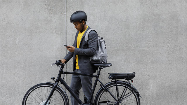 Young man standing by electric bicycle using smartphone 