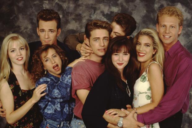 The "Beverly Hills, 90210" cast - from left, Jennie Garth, Gabrielle Carteris, Luke Perry, Jason Priestley, Brian Austin Green, Shannen Doherty, Tori Spelling and Ian Ziering - poses for a portrait on set in September 1991 in Los Angeles, California. 