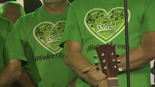 Individuals wear green t-shirts that say "#DalerStrong" underneath a green heart with musical notes inside it. 