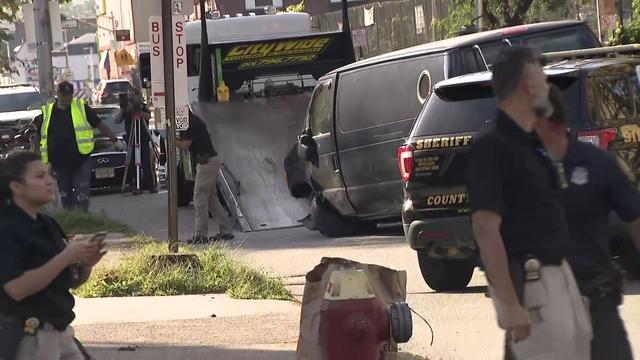 Investigators examine the scene near a black van on a street in Paterson. 