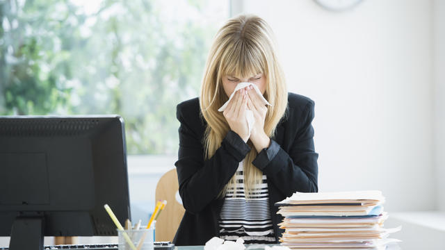 Businesswoman blowing nose in office 