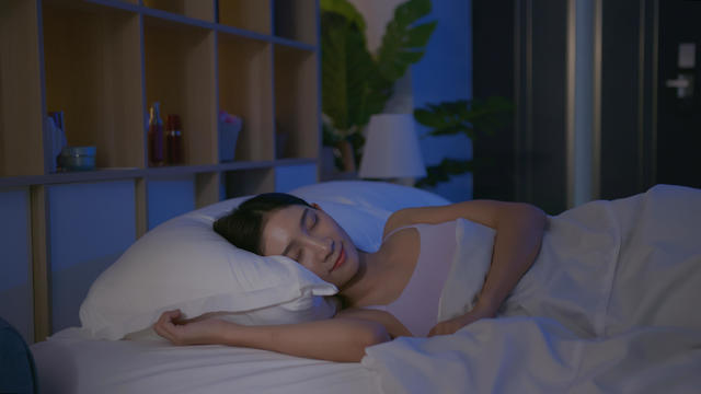 Woman sleeping in bed at night, side sleep position 